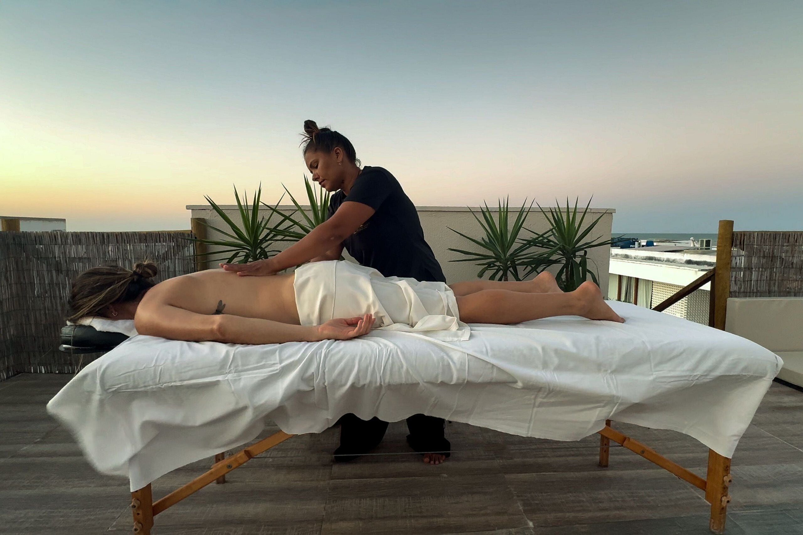 Sesión de masoterapia en una azotea con vistas al océano.