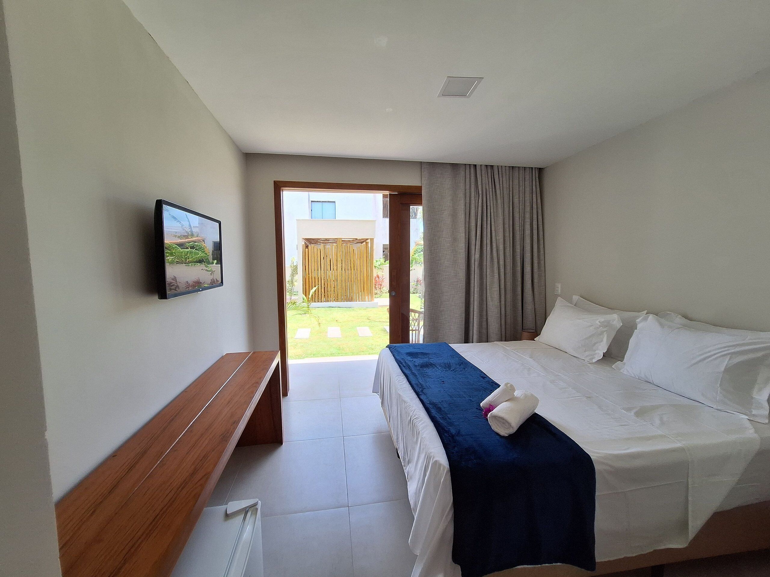 Een hotelkamer met een bed, een bankje, een televisie en uitzicht.