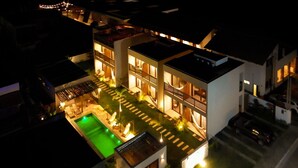 Un edificio moderno de varios pisos con piscina, iluminación exterior y un porche cubierto.
