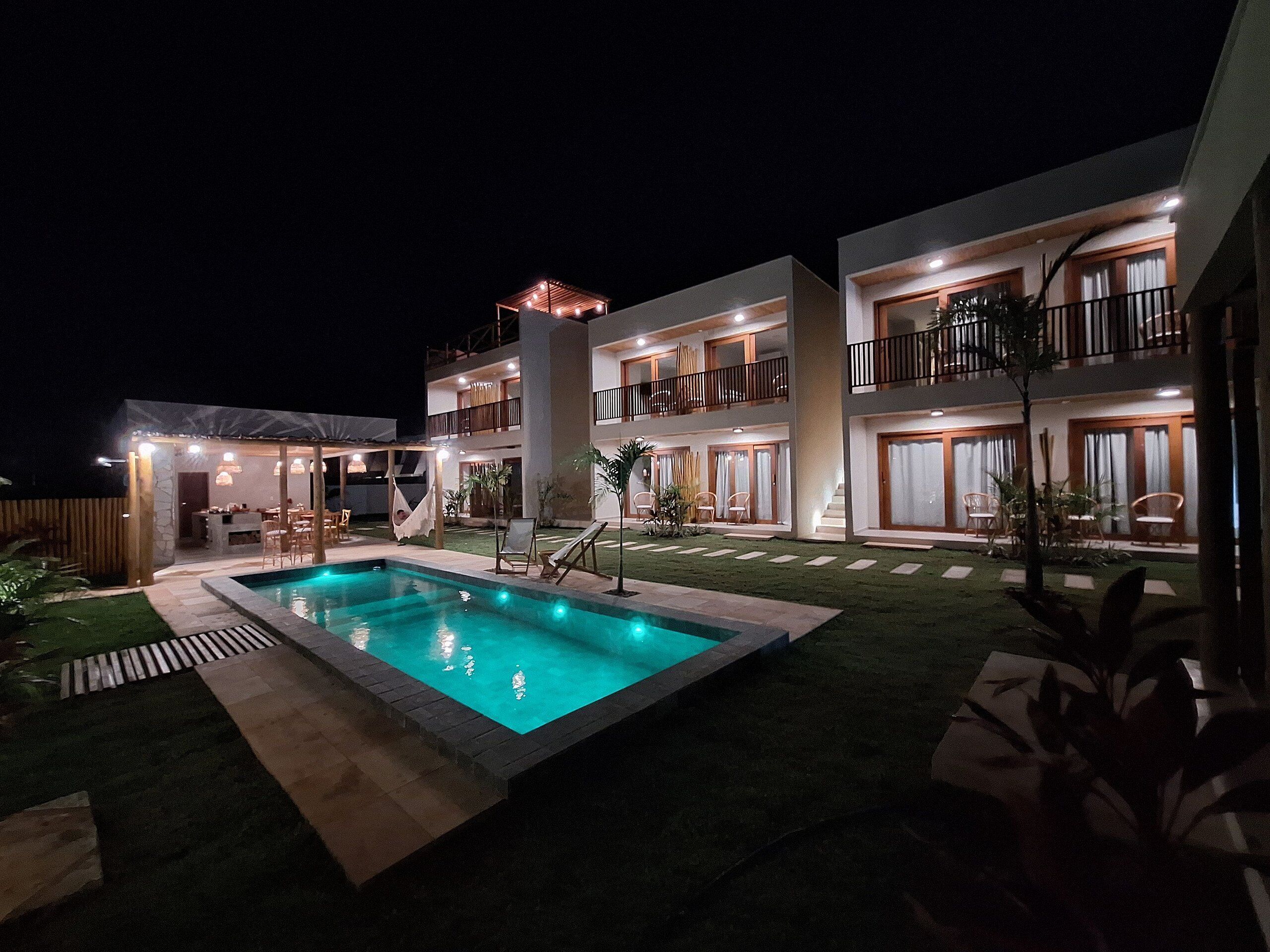 Un hotel su più piani con piscina, area salotto all'aperto e un patio ben illuminato.