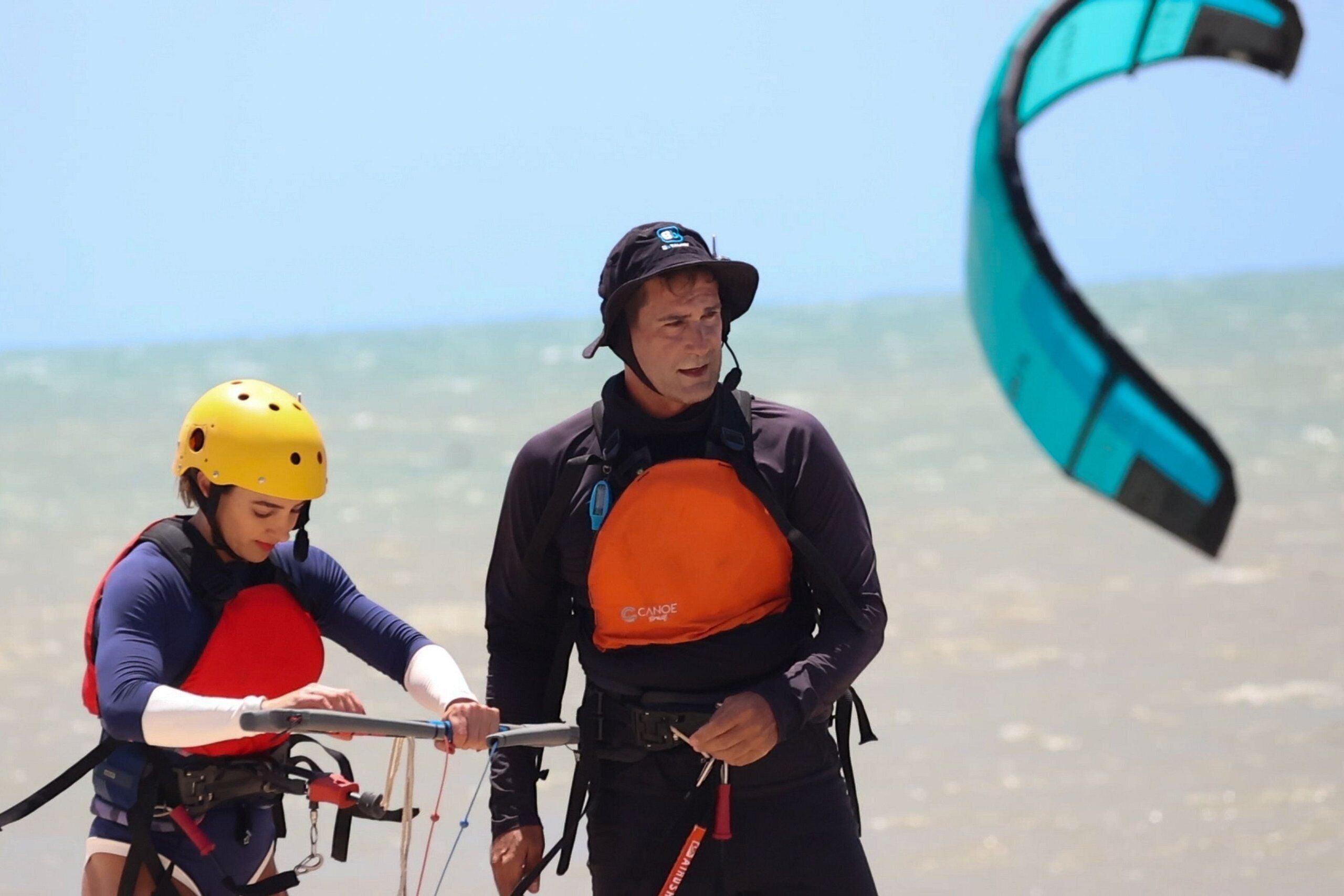 Two people on a beach with a kite.