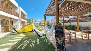 Um pátio com rede, piscina e área de estar externa.
