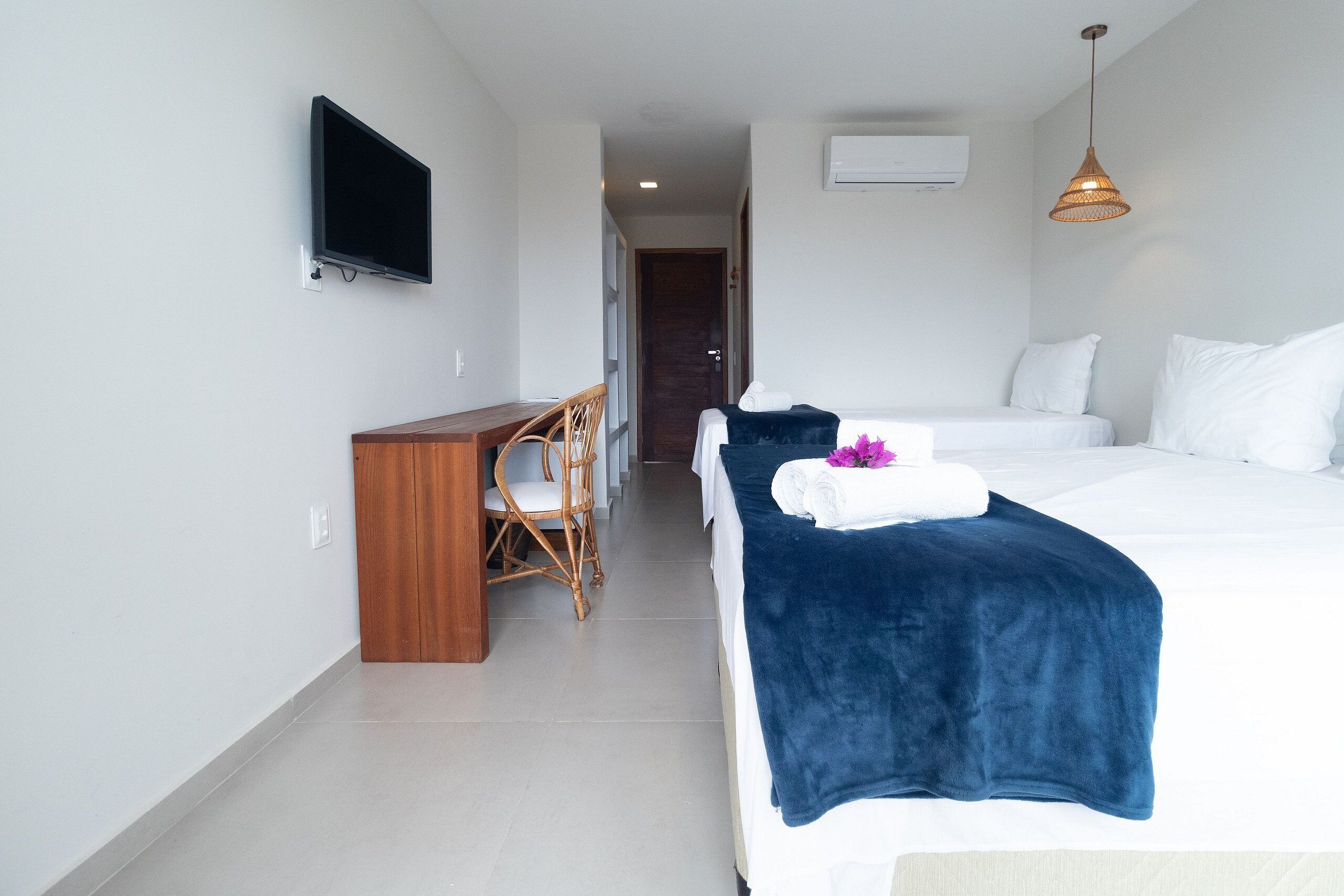 Una camera d'albergo con un letto, una scrivania, una sedia, una televisione e una lampada a sospensione.