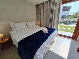 Habitación de hotel con cama, mesita de noche y vista a un jardín.