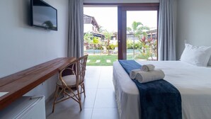 Habitación de hotel con cama, escritorio, silla y vistas a un jardín y edificios.