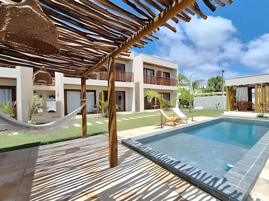 Un espace piscine équipé d’un hamac, de chaises longues et d’un bâtiment doté de balcons.