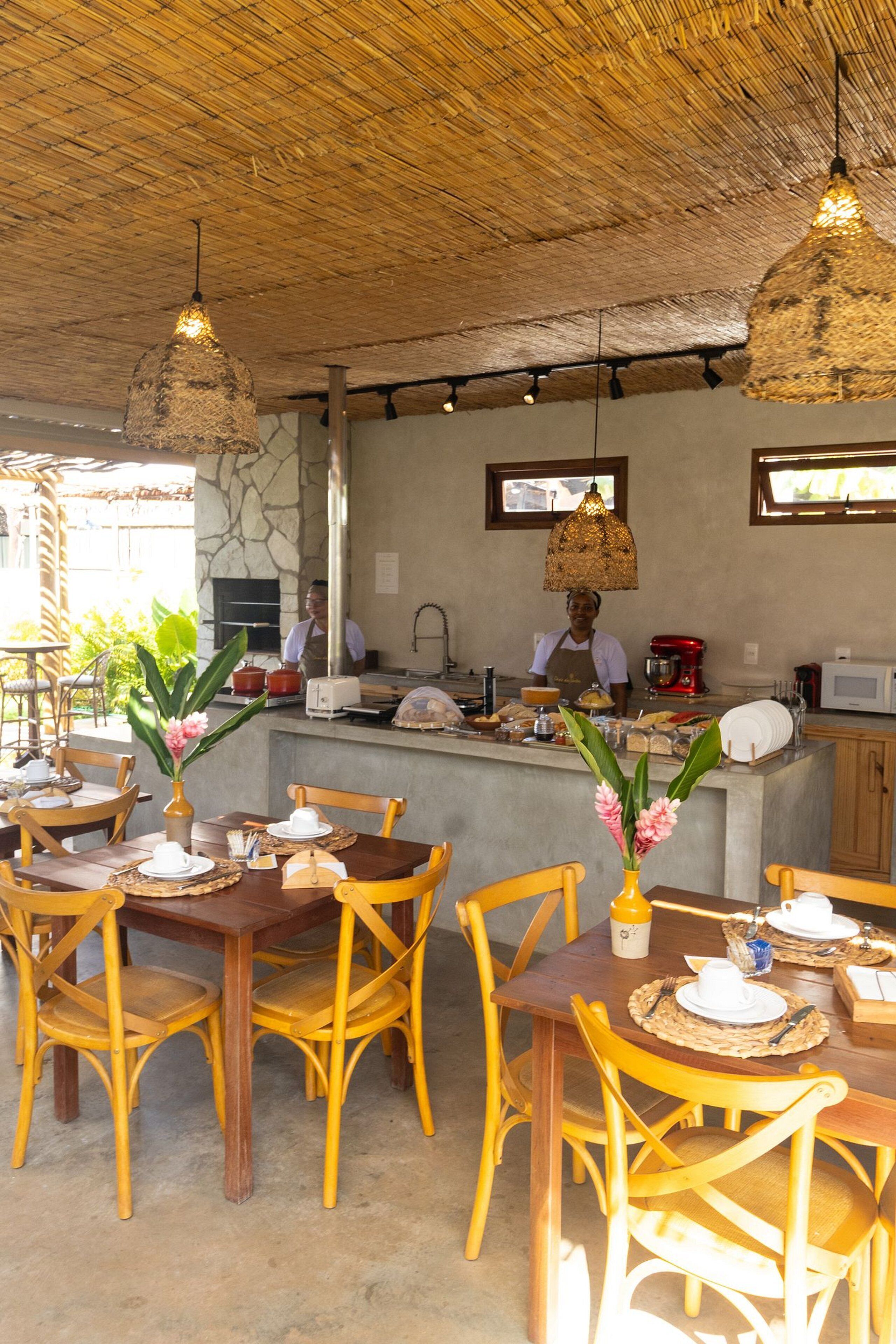 A restaurant with wooden tables and chairs, a bar area, and a kitchen in the background.