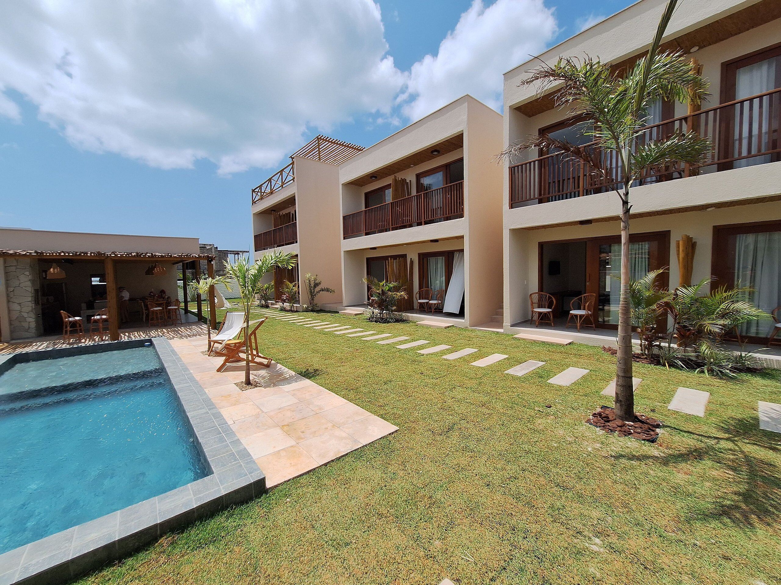 Un hotel con piscina, mobiliario exterior y césped bien cuidado.
