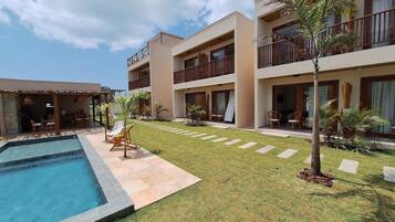 Un hotel con piscina, mobiliario exterior y césped bien cuidado.