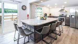 A modern kitchen with a large island, bar stools, and a view of the outdoors. - Island House on Lake Moraine (Madison)