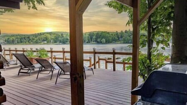 A wooden deck with lounge chairs overlooking a river. - Island House on Lake Moraine (Madison)