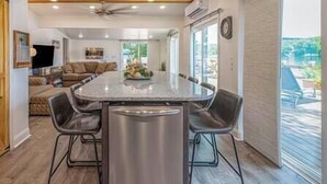 A kitchen with a central island, bar stools, and a refrigerator. - Island House on Lake Moraine (Madison)