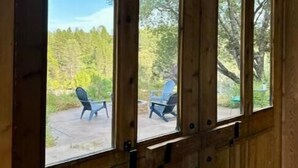 A wooden-framed window with a view of outdoor seating and trees. - Rustic Studio Getaway in the California Gold Country - Pet Friendly (Penn Valley)