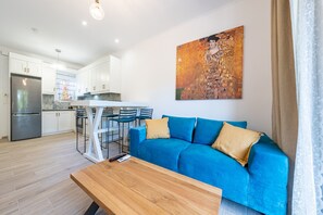 Un salon moderne avec un canapé bleu, une table basse en bois et un tableau accroché au mur.
