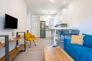 Une cuisine moderne avec des meubles blancs, un réfrigérateur en acier inoxydable et un coin bar avec des tabourets.