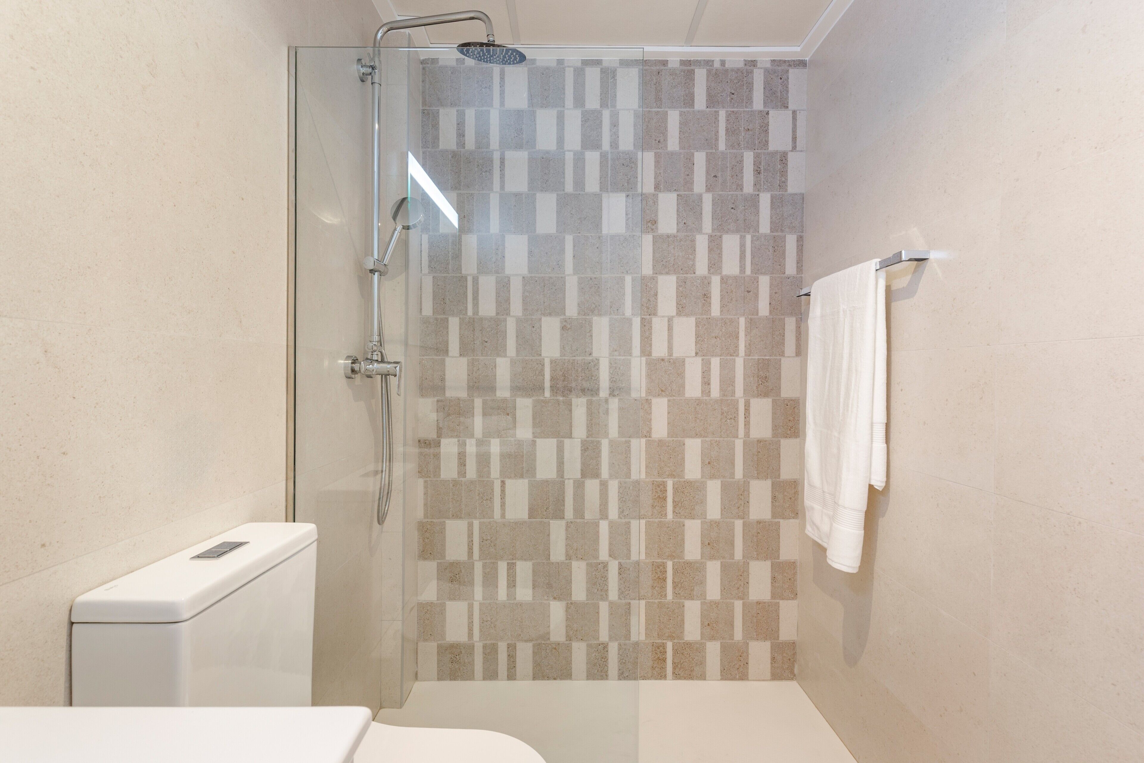 Un baño con cabina de ducha de vidrio, inodoro y perchero para toallas.