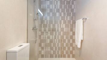 Un baño con cabina de ducha de vidrio, inodoro y perchero para toallas.