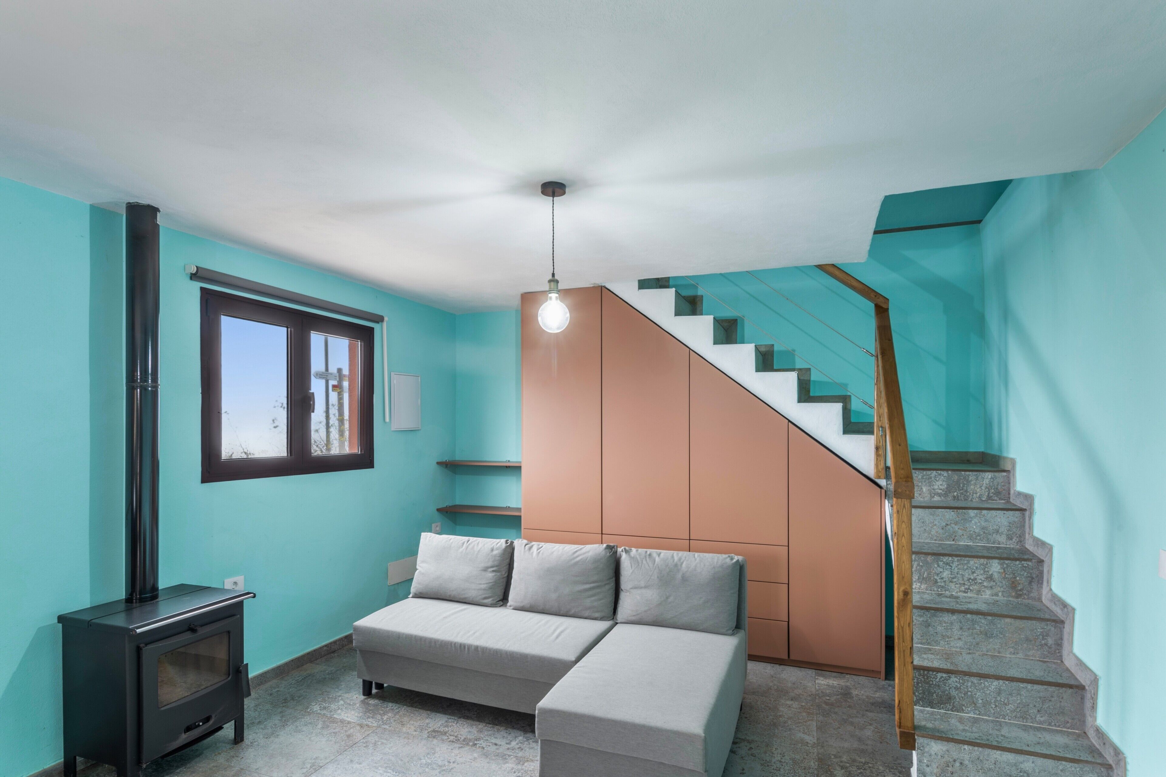 Un interior moderno con un sofá, una escalera y un calefactor empotrado.