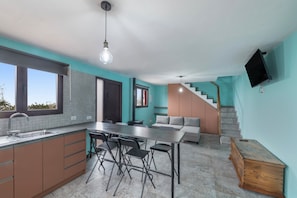 Une cuisine moderne avec un coin repas, un escalier et un téléviseur fixé au mur.