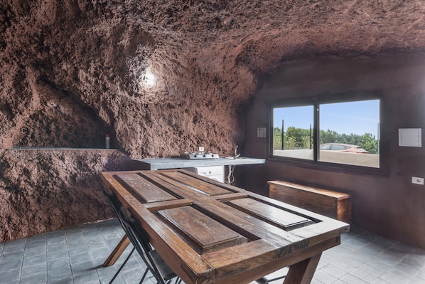 Une cuisine rustique avec un mur en pierre, une table en bois et une fenêtre donnant sur un paysage agréable.