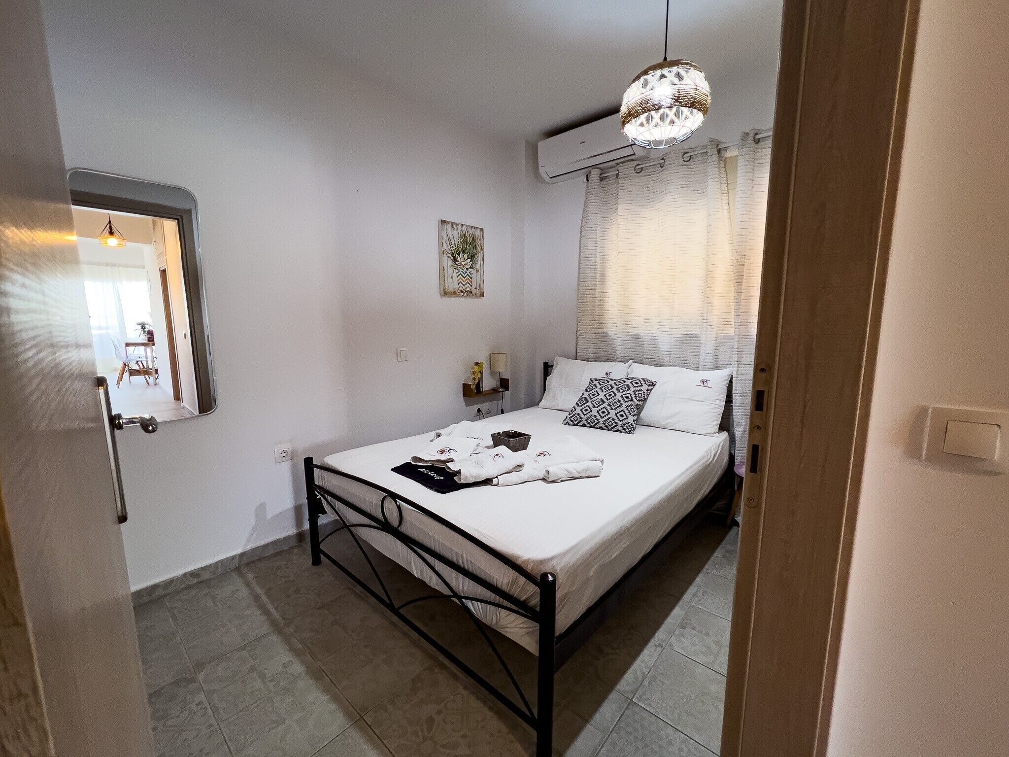 Un dormitorio con una cama, una mesita de noche, una lámpara colgante y un equipo de aire acondicionado.