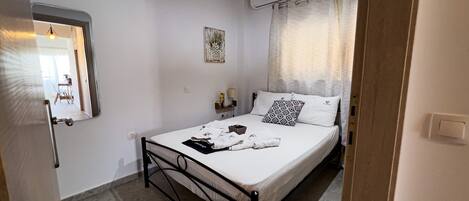Un dormitorio con una cama, una mesita de noche, una lámpara colgante y un equipo de aire acondicionado.