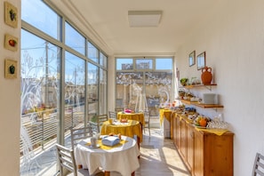 A dining area with large windows, a wooden cabinet with dishes, and a table with a yellow tablecloth. - Bed and Breakfast 'Tallyho Melograno' with Shared Terrace, Wi-Fi and Air Conditioning (Salve)