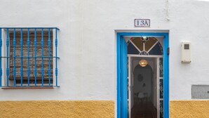 A building entrance with a blue door, a window with blue bars, and a sign above the door.