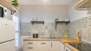 A kitchen with patterned tiles, a sink, wooden countertops, and cabinets.