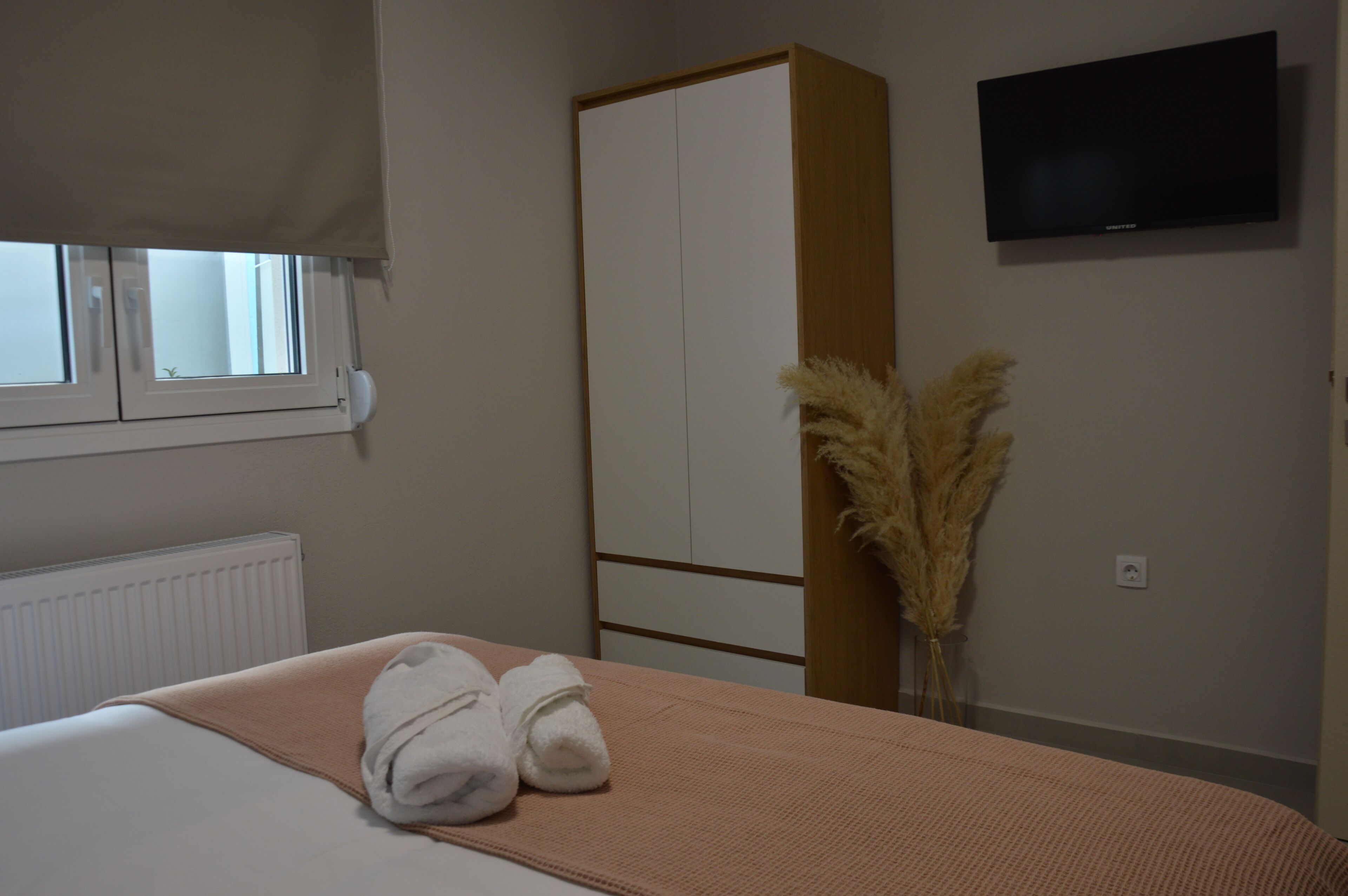 Ein Hotelzimmer mit Bett, Schrank, Fernseher und einem Fenster mit Jalousien.