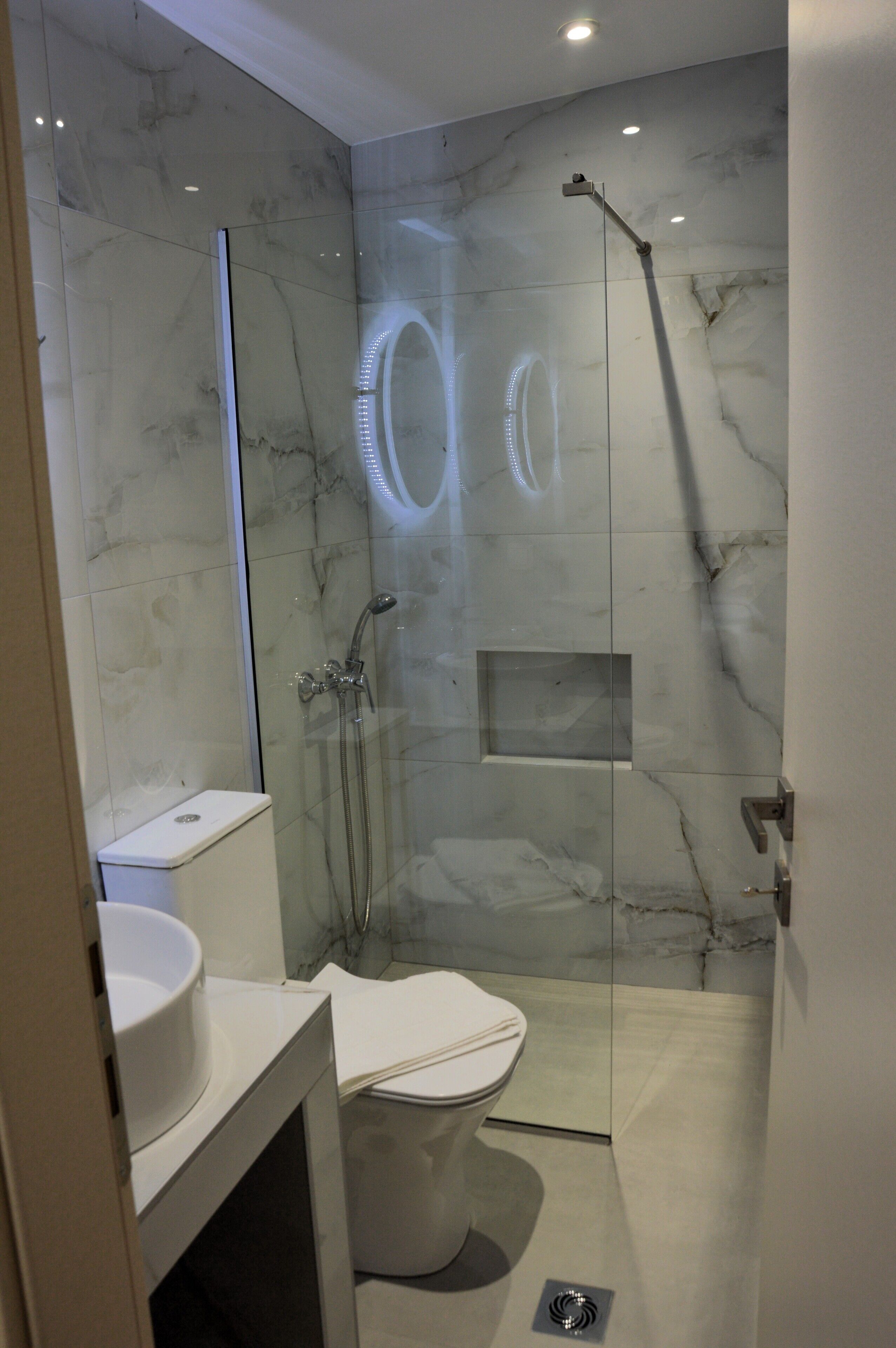 Une salle de bain moderne avec une douche à parois de verre, des toilettes et un lavabo.