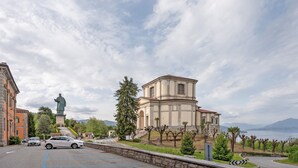 Un bâtiment surmonté d’une statue, une route sinueuse et une étendue d’eau en arrière-plan.