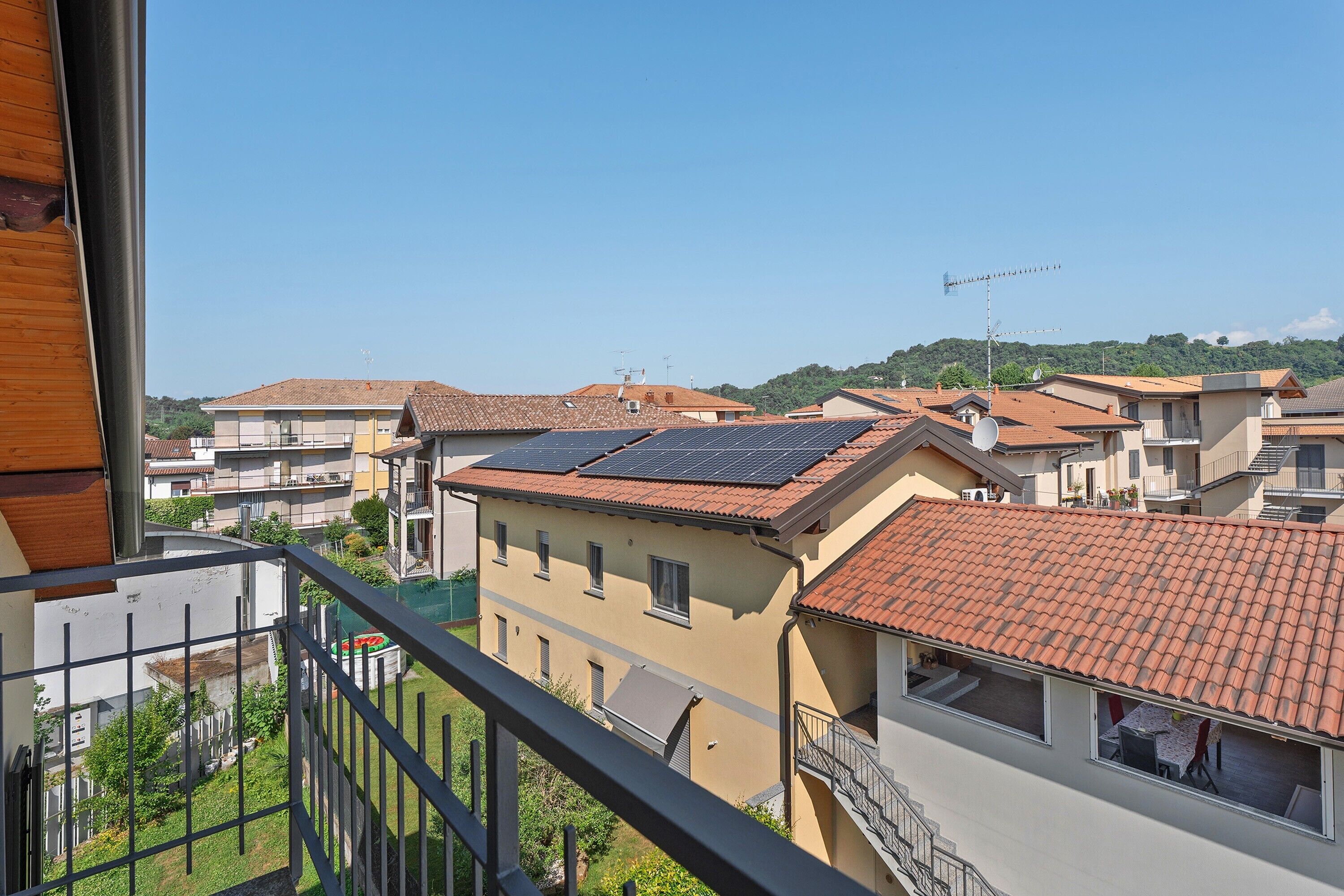 Un quartier résidentiel composé de plusieurs immeubles, dont certains sont dotés de panneaux solaires, et un balcon avec une rambarde en métal.