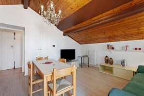 A cozy living room with a wooden ceiling, a dining table with chairs, a television, and a bookshelf. - Apartment 'Comodo, Pratico E Tranquillo' with Mountain View, Wi-Fi and Air Conditioning (Arona)