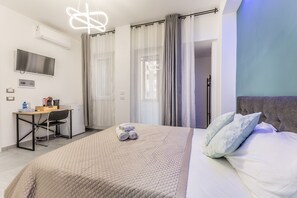 Une chambre d’hôtel avec un lit, un bureau, une télévision et des rideaux.