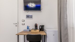 A small room with a desk, chair, television, coffee maker, and a mini-fridge. - Room 'Gordiani Guest House - Green' with Balcony, Wi-Fi and Air Conditioning (Roma)