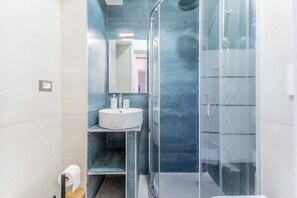 Une salle de bain moderne avec une douche à parois de verre, un lavabo blanc et un miroir.