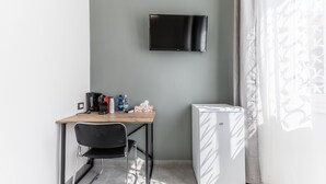 Une petite pièce comprenant un bureau, une chaise, un téléviseur et un réfrigérateur.