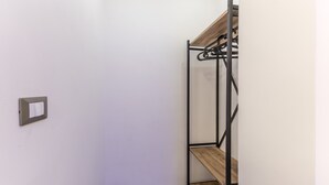 Une pièce avec un lit superposé, un interrupteur fixé au mur et une étagère en bois.