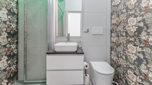 Une salle de bain équipée d’une douche, d’un lavabo, de toilettes et d’un miroir.