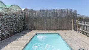 A rectangular pool with a wooden deck, surrounded by a wooden fence and a mesh barrier. - Cottage 'Casita de Ana' with Private Pool, Wi-Fi and Air Conditioning (Conil de la Frontera)