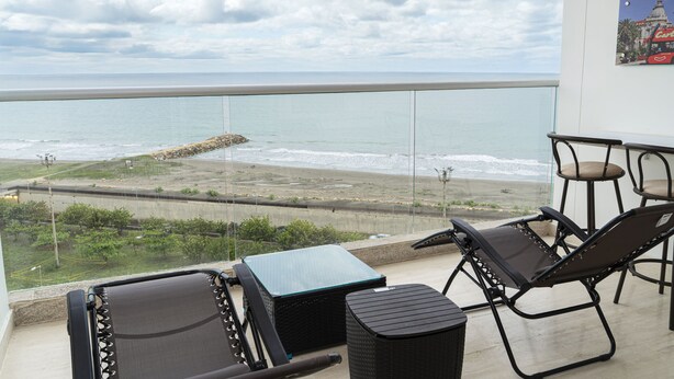 A balcony with a view of the ocean, two chairs, a small table, and a wicker basket. - Charming Loft Apartment in Cartagena de Indias (Cartagena de Indias)