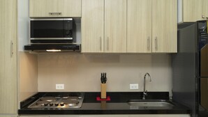 A kitchen with light wood cabinets, a black countertop, a microwave, a stove, a sink, and a knife block. - Charming Loft Apartment in Cartagena de Indias (Cartagena de Indias)
