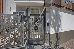 A gated entrance with a geometric metal design, a white door, and a number sign '216' on the wall.