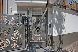 A gated entrance with a geometric metal design, a white door, and a number sign '216' on the wall.