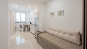 Ein helles, modernes Zimmer mit einem Bett, einem kleinen Tisch und einem Stuhl.
