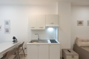 Cozinha compacta com pia, armários, coifa e uma pequena mesa com cadeiras.