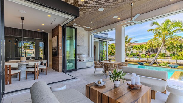 A modern outdoor living area with a pool, seating, and a barbecue. - NEW LUX WATERFRONT HOME- Walk to 5th Ave (Naples)