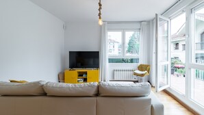 Moderni olohuone, jossa on sohva, televisio ja keltainen kaappi.