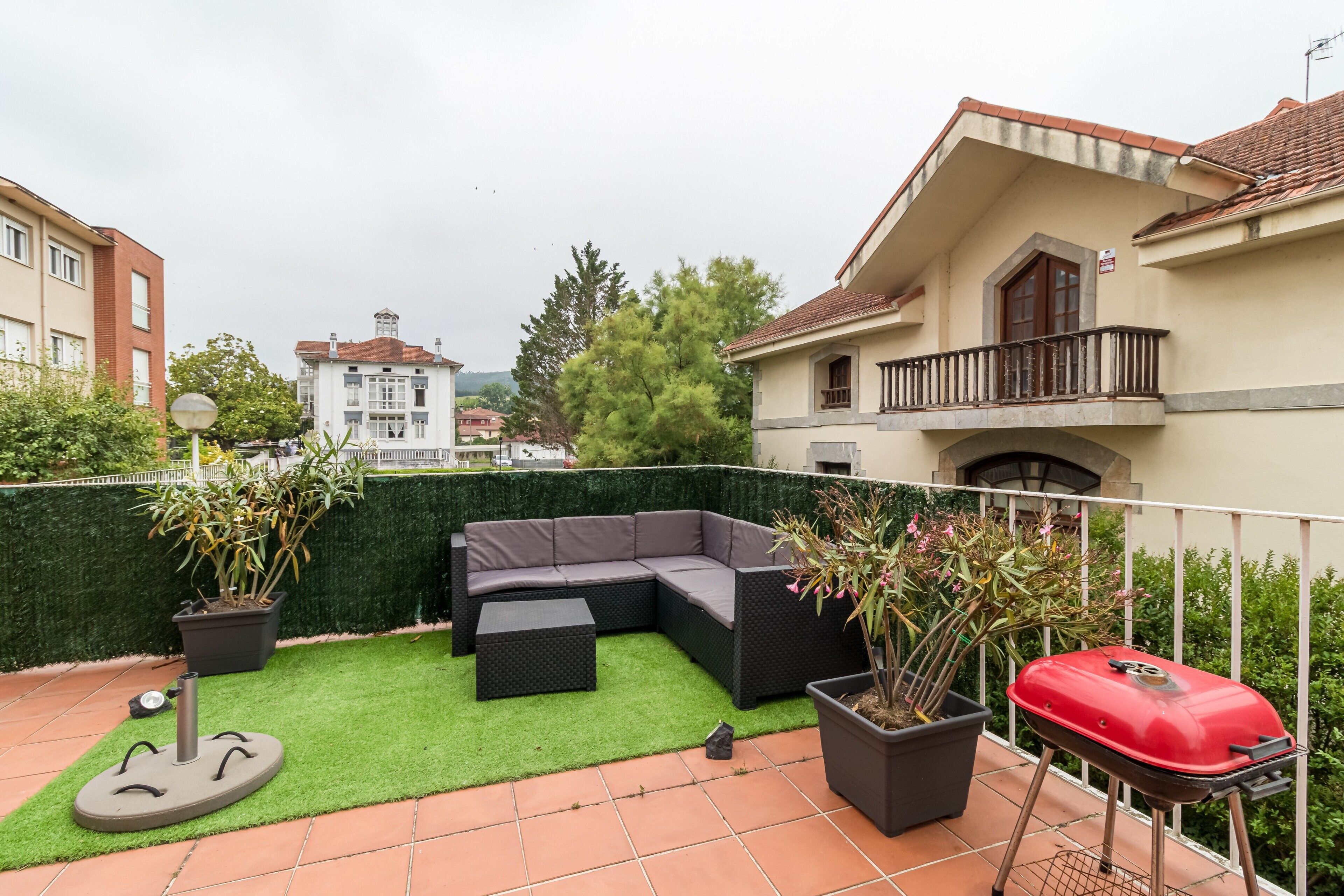 Terraza en la azotea con un sofá modular, una parrilla de barbacoa y plantas en macetas.